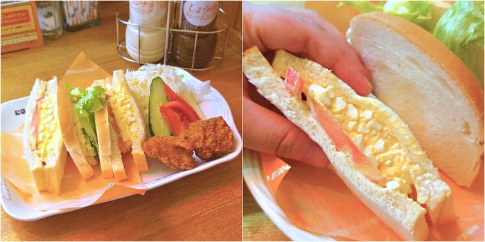 卵サンドイッチと野菜、フライドチキンが添えられたカフェメニュー。手に持たれたサンドイッチのクローズアップも含む。