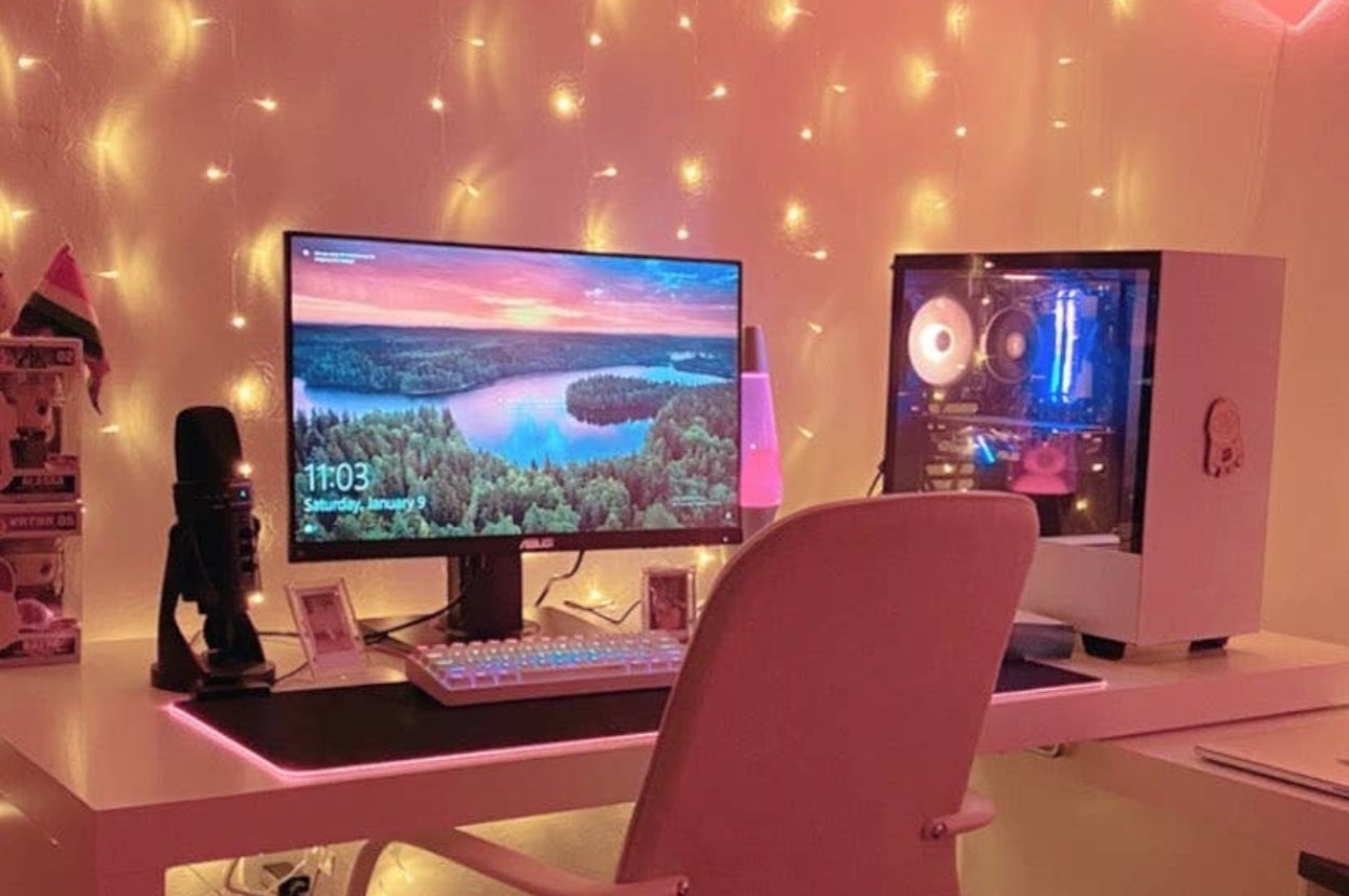 Stylish computer setup with glowing lights, featuring a monitor, keyboard, microphone, and gaming PC on a modern desk