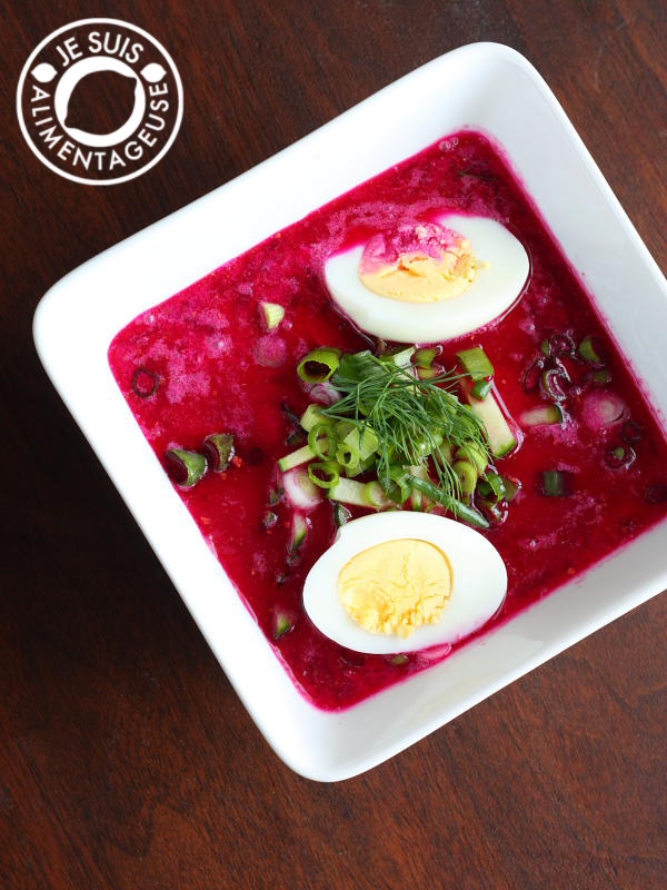 White bowl with cold beet soup, garnished with green onions, dill, and halved boiled eggs. Text in corner: "Je Suis Alimentageuse."