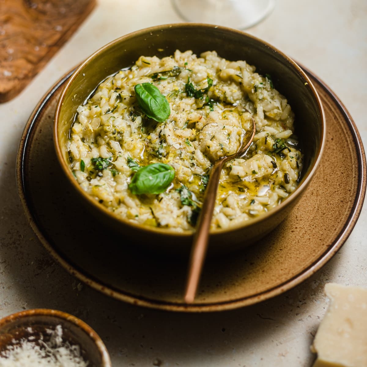A bowl of creamy risotto garnished with fresh basil, served with grated cheese on the side