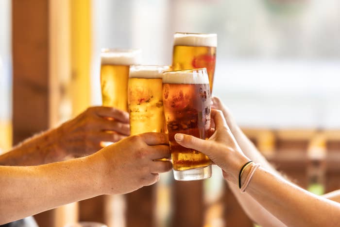 People clinking glasses of draft beer in a celebratory toast, with a warm, inviting atmosphere