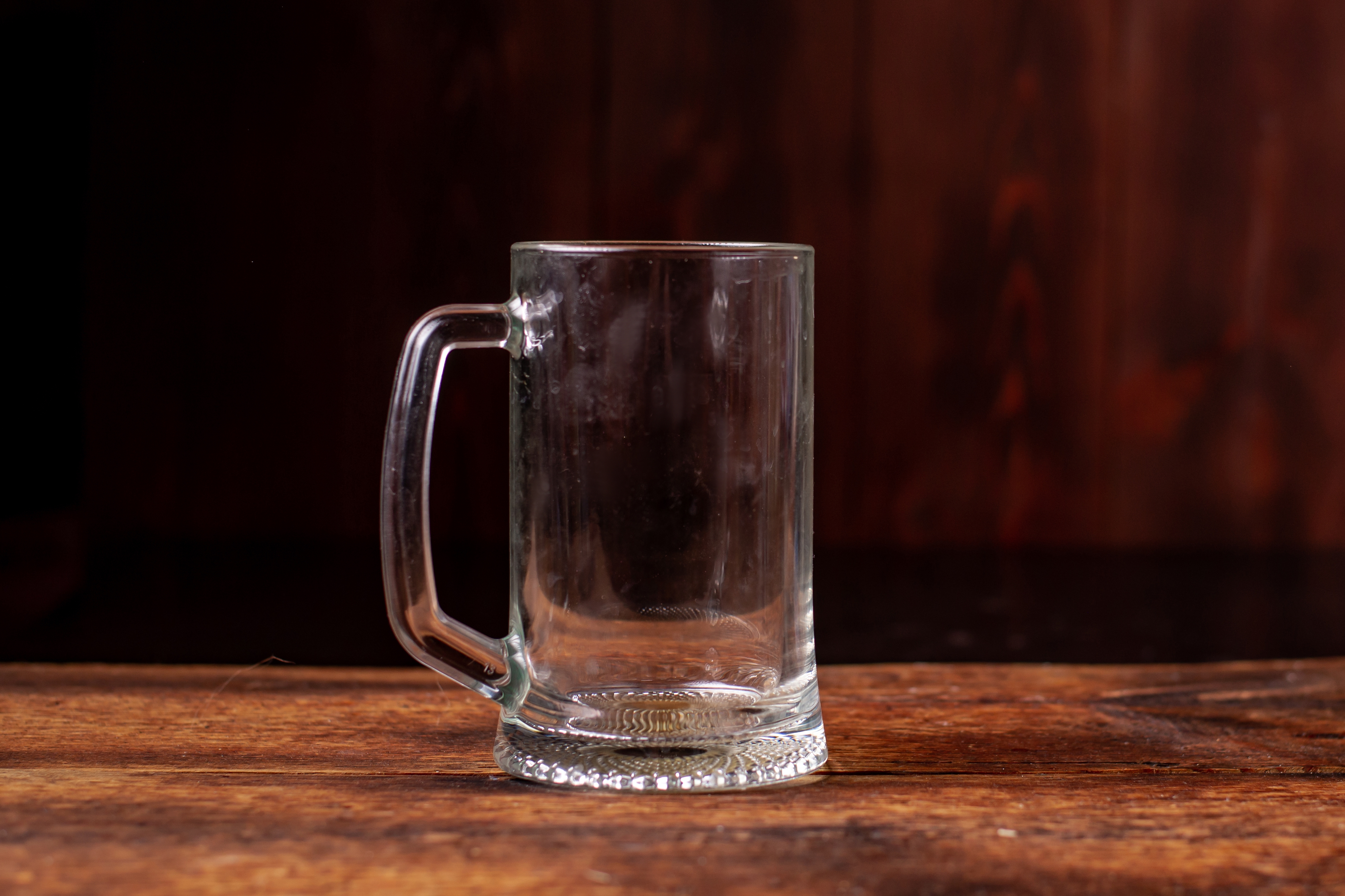 Empty glass beer mug on a wooden table with a dark background