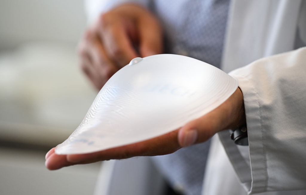 En person i et laboratorifrakk har et silikonbrystimplantat, og viser frem sin glatte, buede design