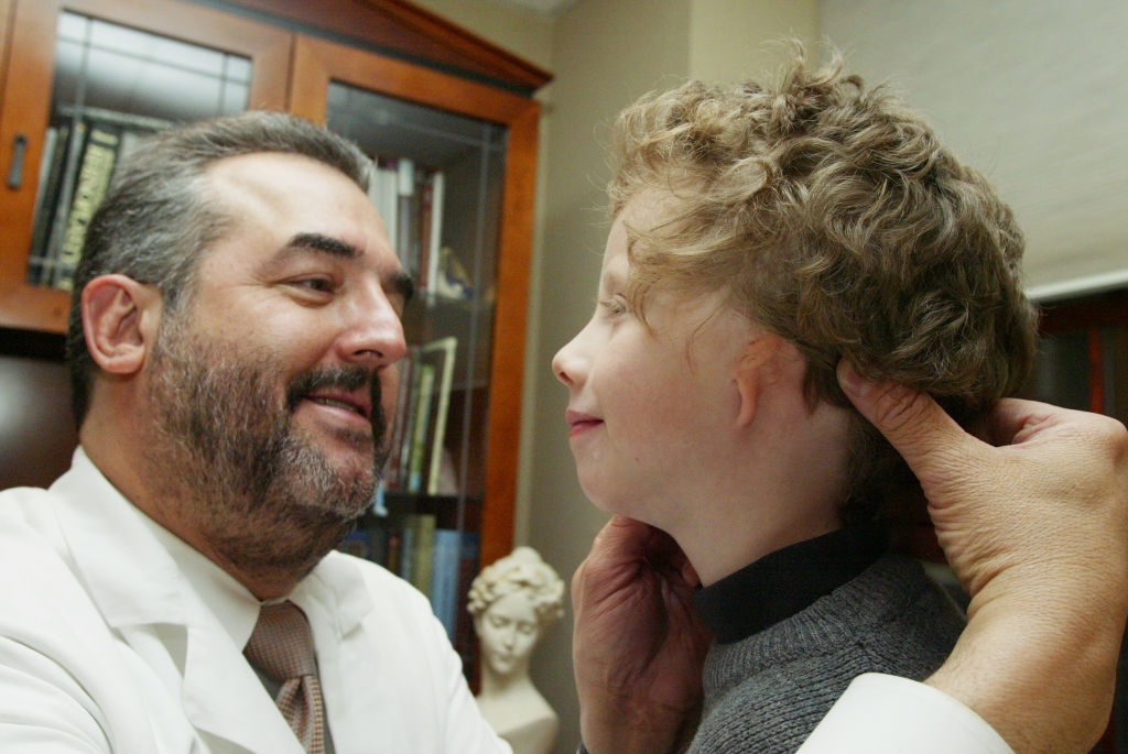 En lege smiler og justerer bandasjene til et barn med krøllete hår, og diskuterer medisinsk fremgang i et varmt kontor omgivelser