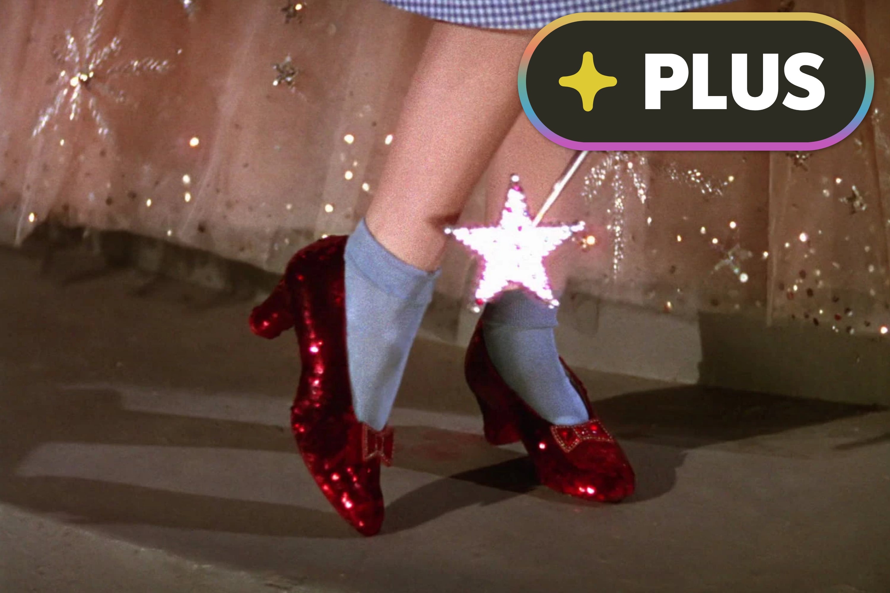 Sparkly red shoes on feet with light blue socks, standing on a shiny floor with a star-tipped wand nearby in a magical setting