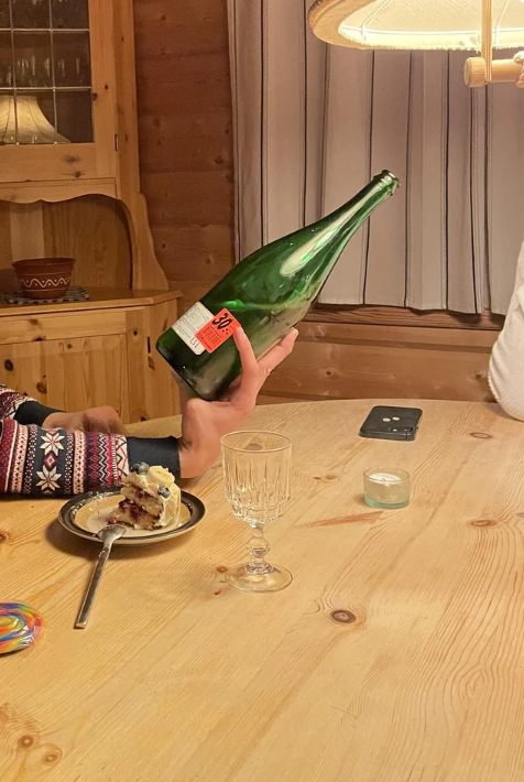 Person successful  patterned sweater holds a ample  greenish  vessel  implicit    a array  with cake, glass, and telephone  successful  cozy woody  room