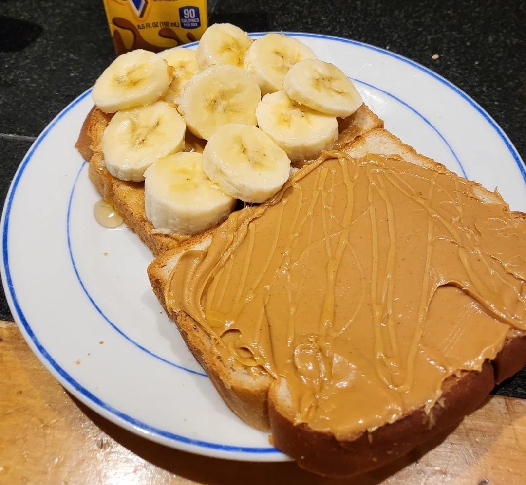 Chocolate milk carton beside a plate with a peanut butter and banana sandwich on whole-grain bread