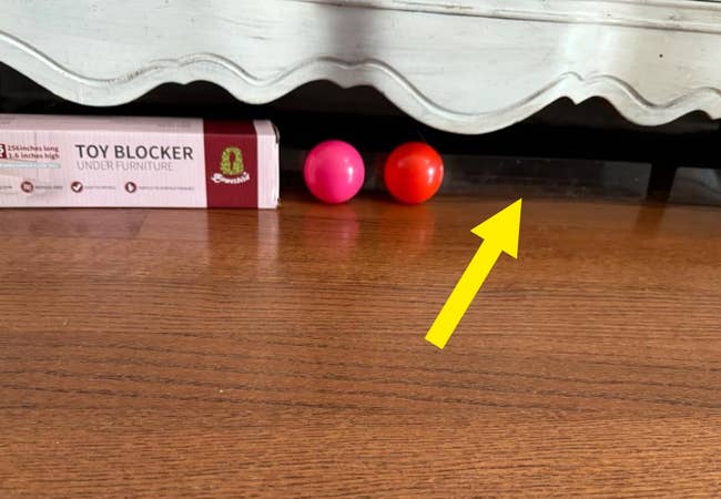 Toy blocker is wedged nether furnishings alongside 2 tiny balls connected a woody floor, preventing toys from rolling underneath