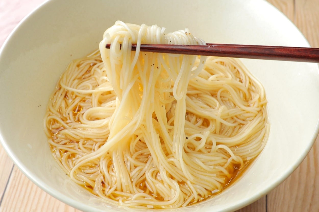 白い器に入った麺を箸で持ち上げているシンプルな盛り付けの食事シーン。
