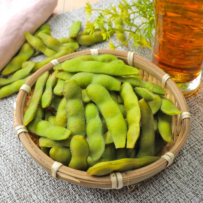 竹のざるに盛られた枝豆と、横に置かれた冷たい飲み物。