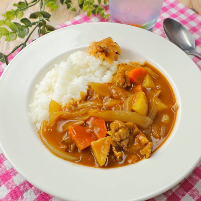 カレーライスの皿。ご飯の横にカレーが盛られ、具材はニンジン、ジャガイモ、肉、玉ねぎが見える。スプーンが横にある。