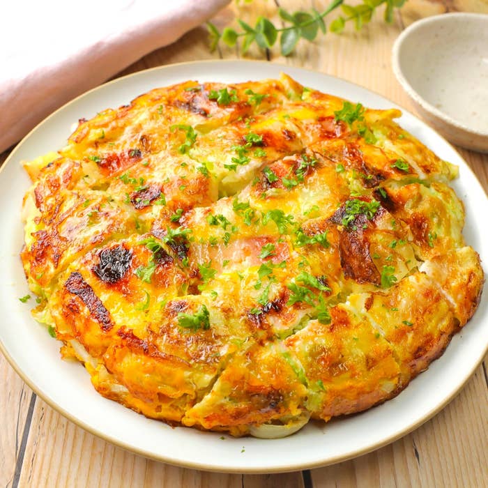 大皿に盛られた焼きたてのスパニッシュオムレツ。パセリがトッピングされ、美味しそうに焼き上がっている。