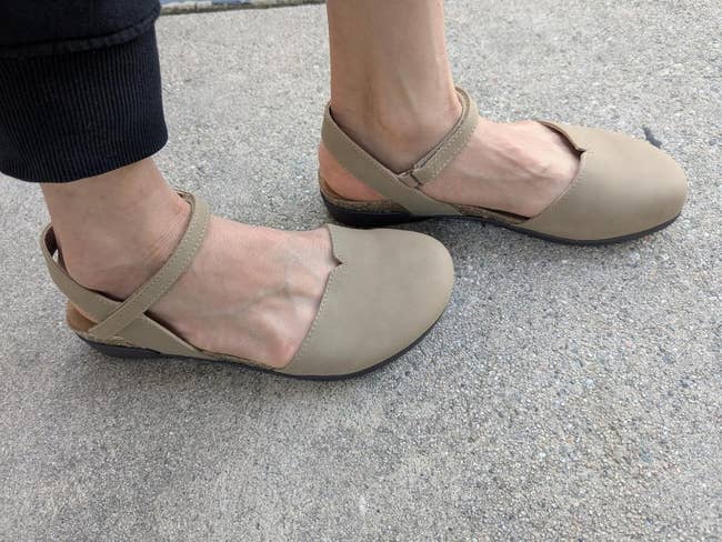 Beige flats with straps shown connected  a idiosyncratic   wearing achromatic  pants for a buying  article
