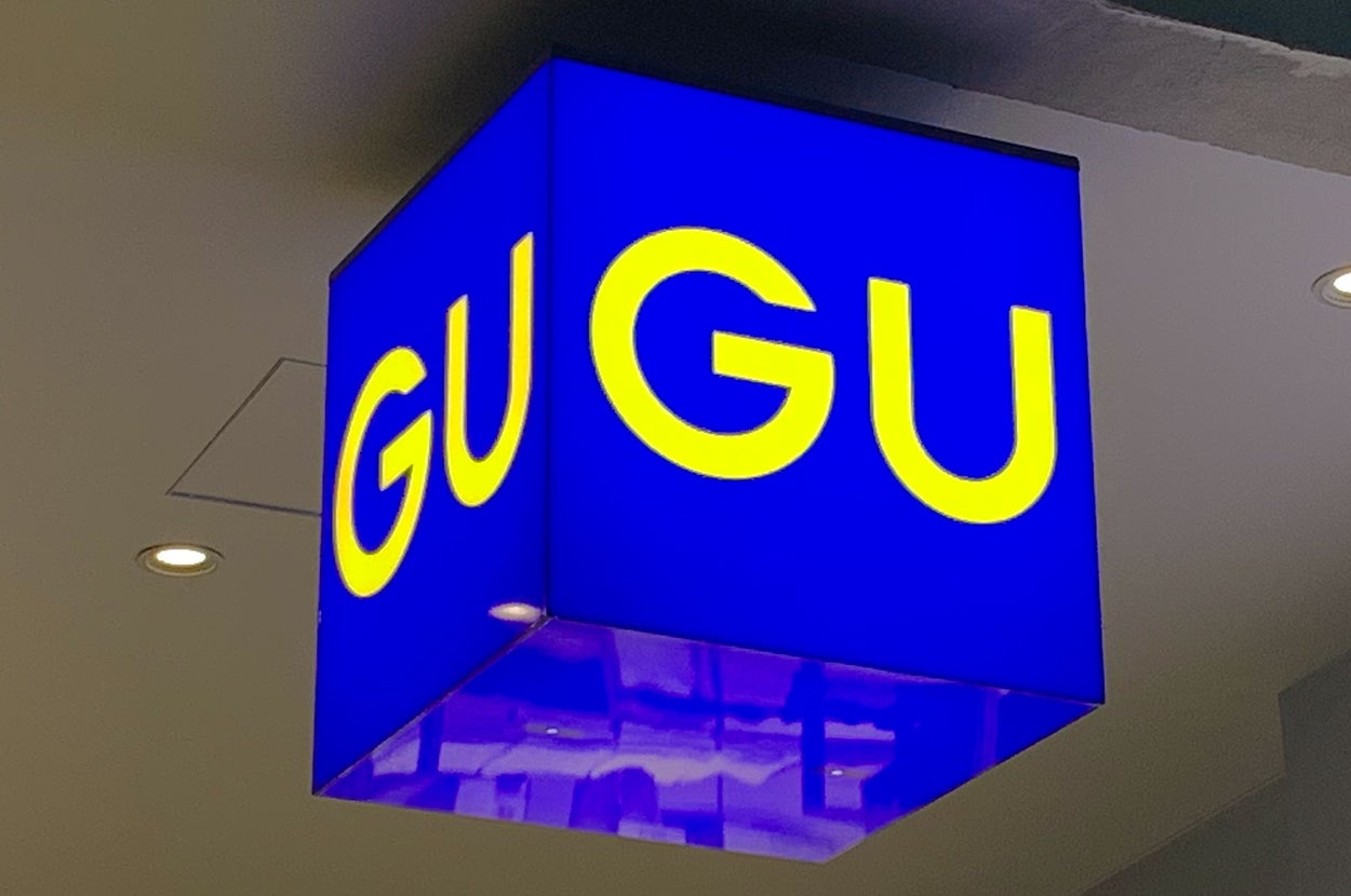 Sign in a retail store with the letters "GU" displayed in yellow on a blue cube