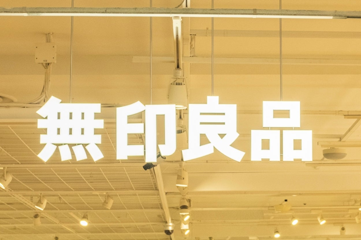 Shoppers browse inside a well-lit, organized store with Japanese signage and various products displayed on shelves