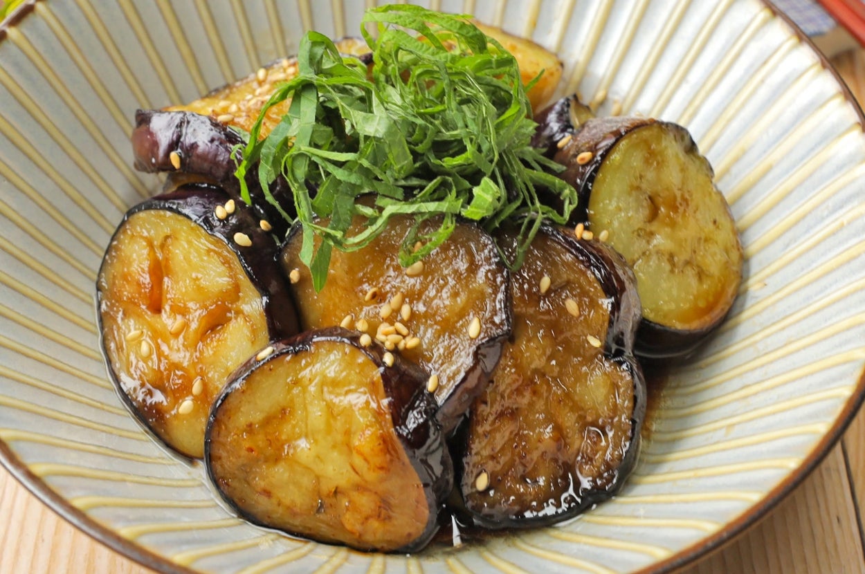 ナスの炒め物が皿に盛られ、上に千切りのシソとゴマがかかっています。