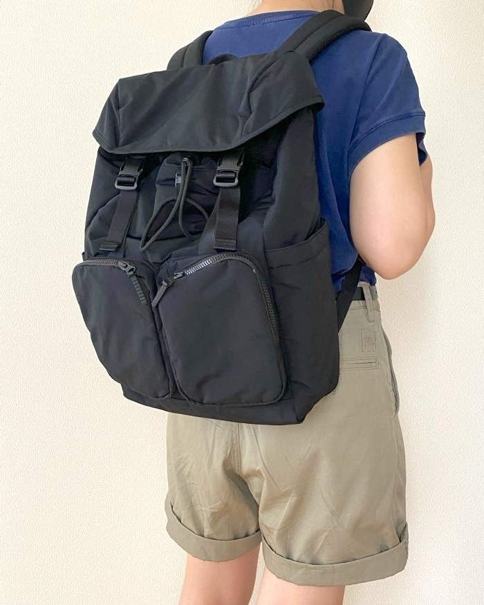 黒いバックパックを背負ったショートパンツとTシャツを着た人物の背面。