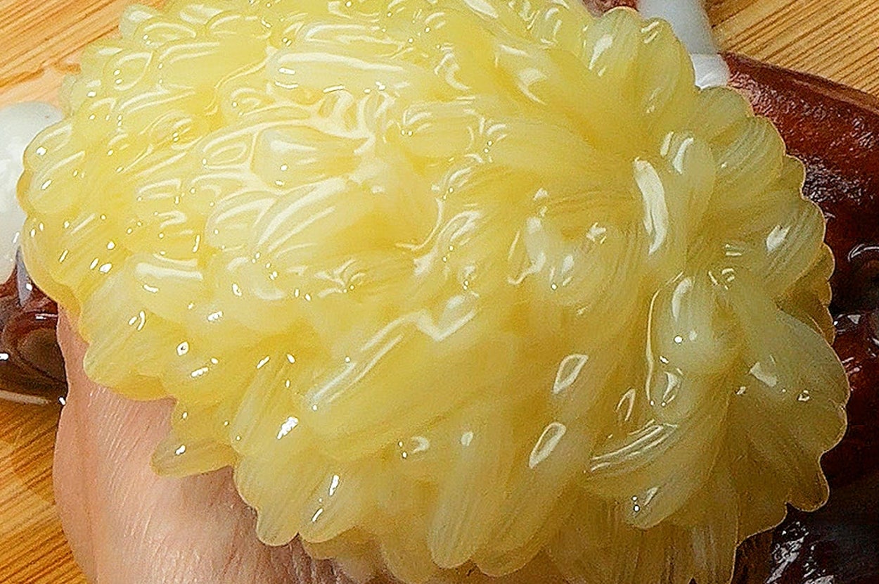 手に持たれた新鮮な生のイカの卵が映っています。