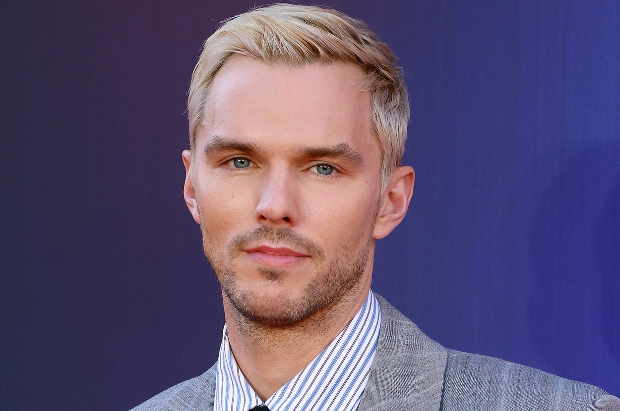 Person in a gray pinstripe suit and black tie at a formal event, posing against a plain backdrop