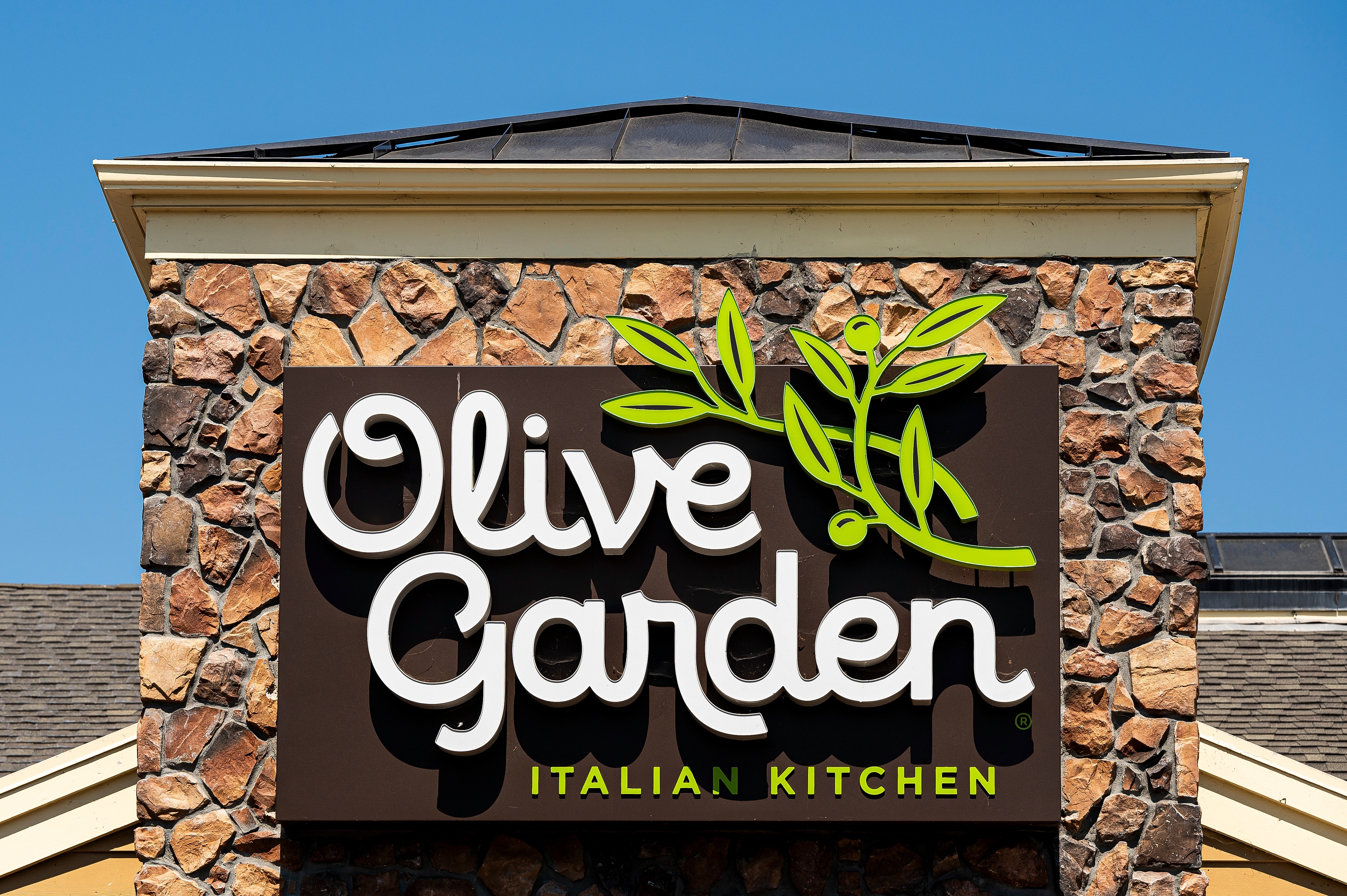 Sign for Olive Garden Italian Kitchen on a building, featuring their logo with green olive branch