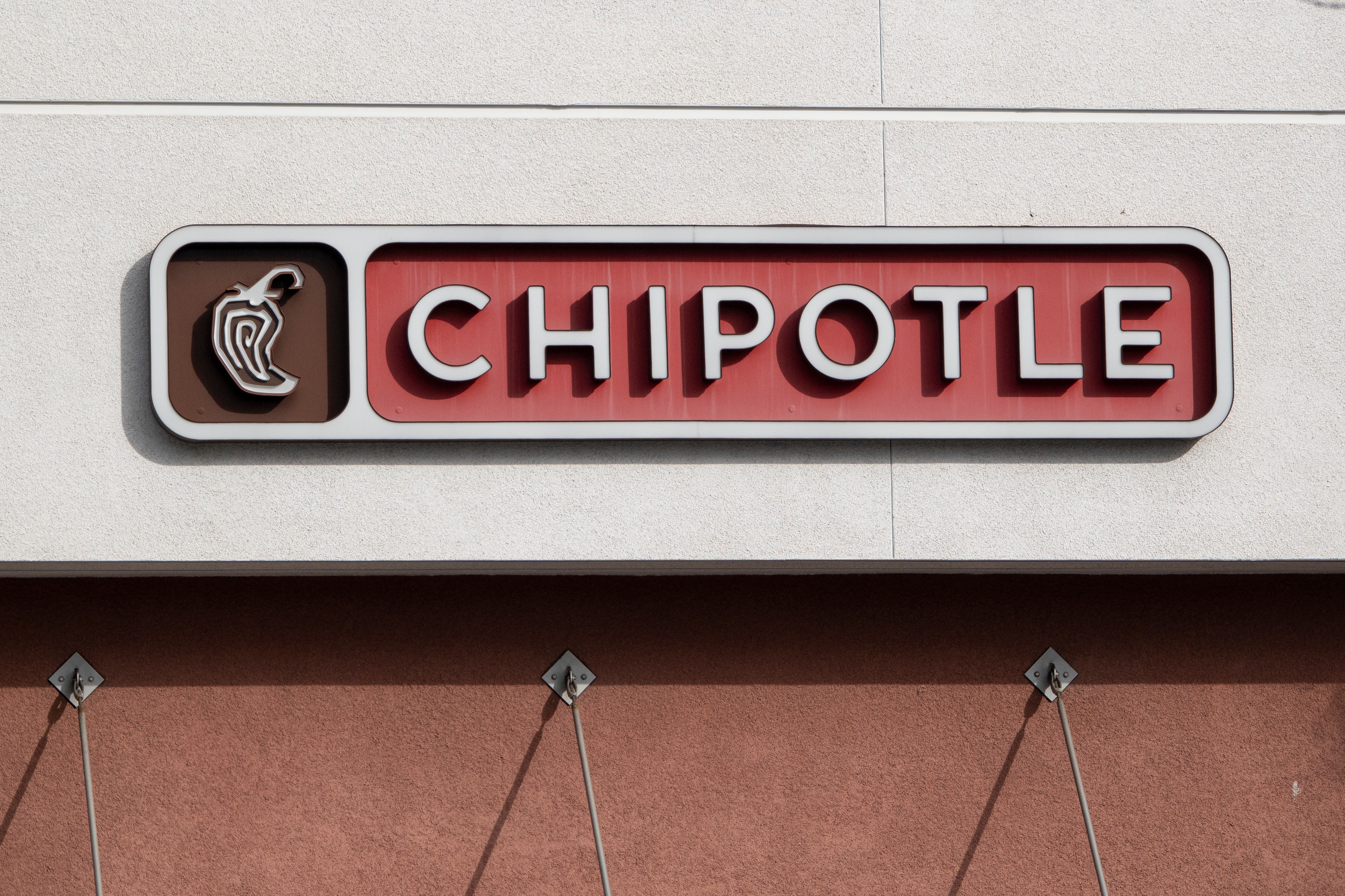 Chipotle restaurant sign on a building exterior, featuring the company's logo and name