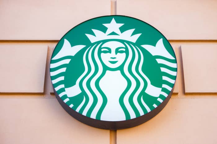 Starbucks logo on a storefront wall, featuring the iconic siren symbol in a circular green sign