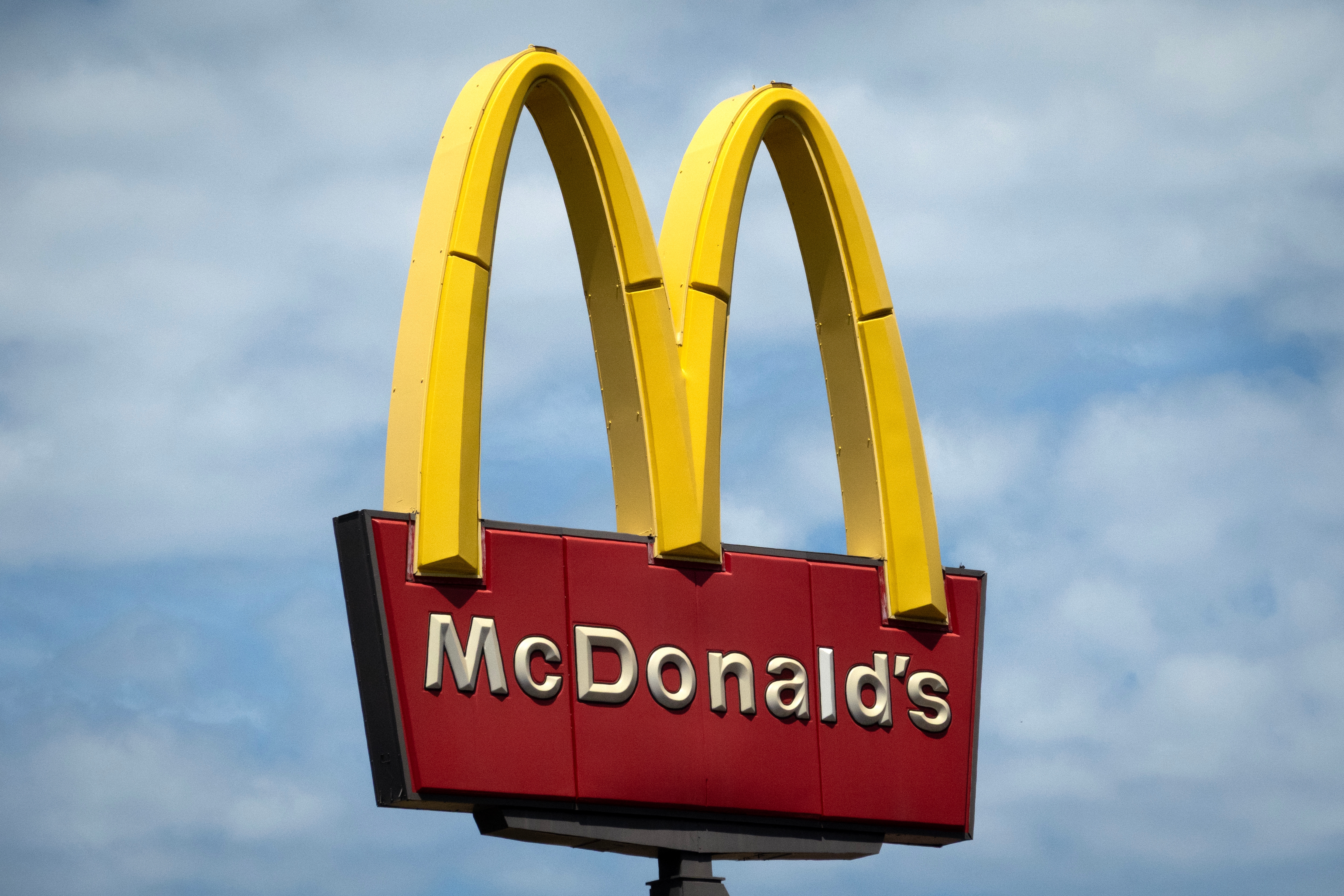 McDonald's logo with golden arches against a cloudy sky background