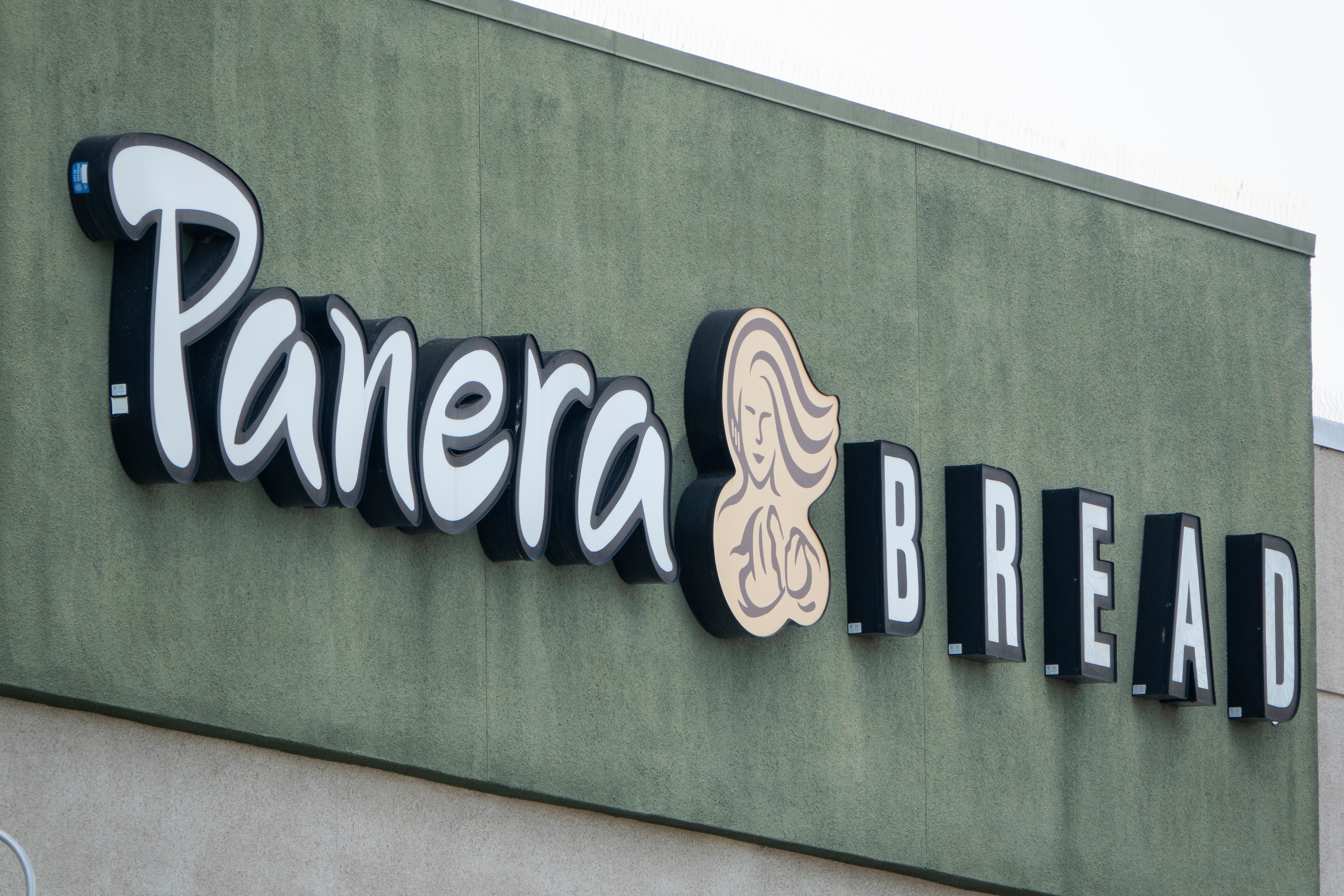 Panera Bread storefront sign on a green building exterior