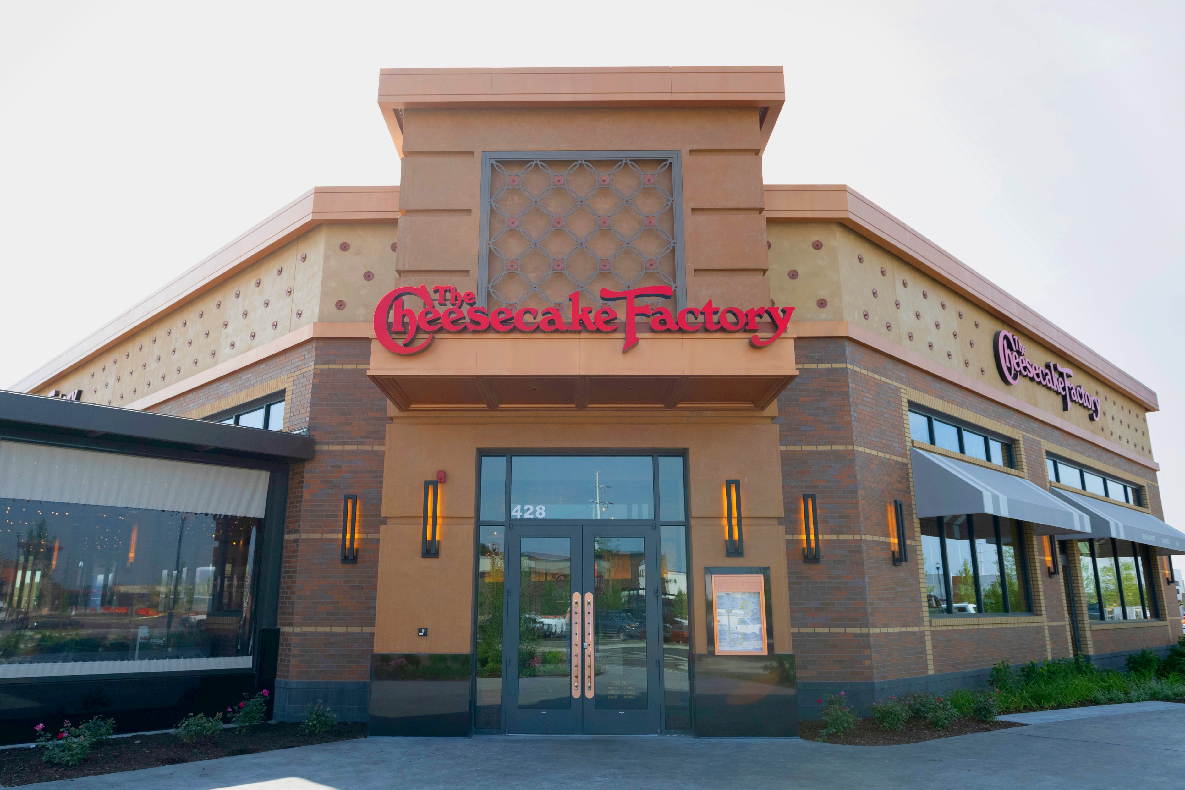 Cheesecake Factory restaurant entrance with distinctive exterior design, featuring signature red signage and large glass doors