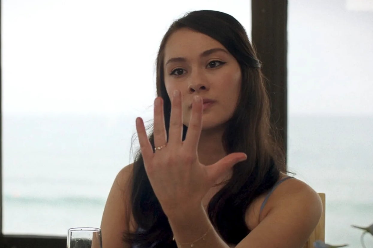 A woman looks at her hand intently, possibly observing a ring
