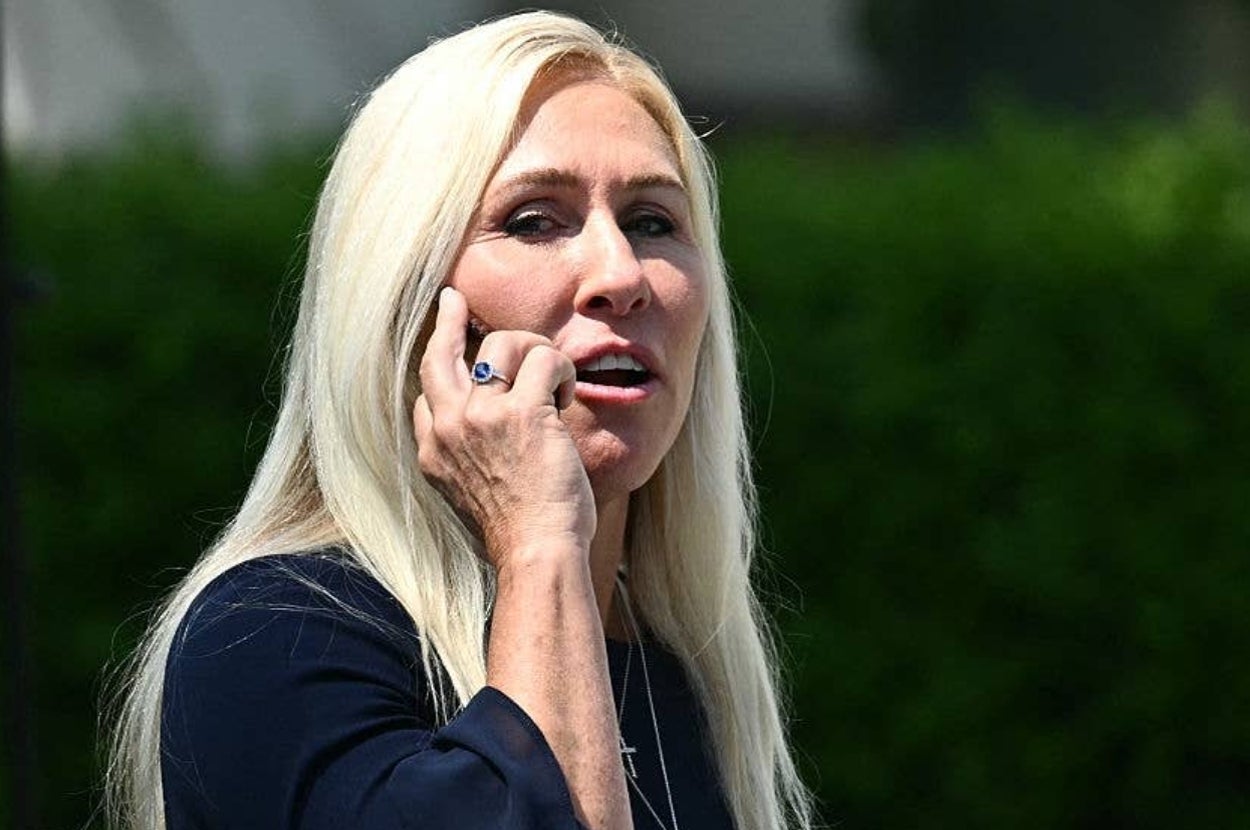 Person talking on the phone outdoors, wearing a dark top with long, straight hair