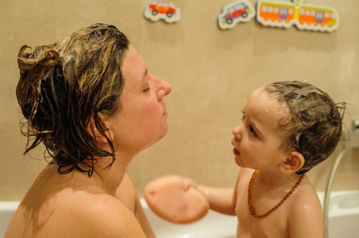Parent and toddler enjoying bath time together, surrounded by toy train decorations on the wall