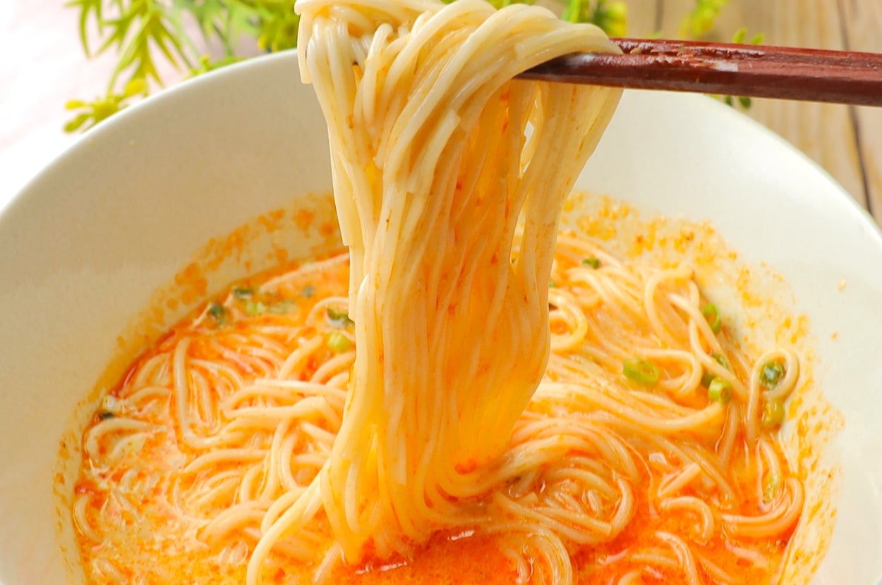箸で持ち上げられたそうめんのボウル。ピリ辛スープが絡んでいます。