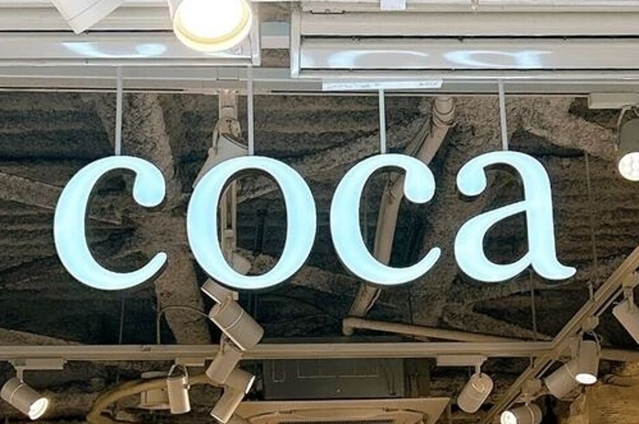 ショップの入り口に「coca」のネオン看板。店内には白いディスプレイのマネキンが並んでいます。