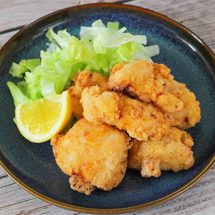 皿に盛られた唐揚げとレモン、キャベツの付け合わせ。