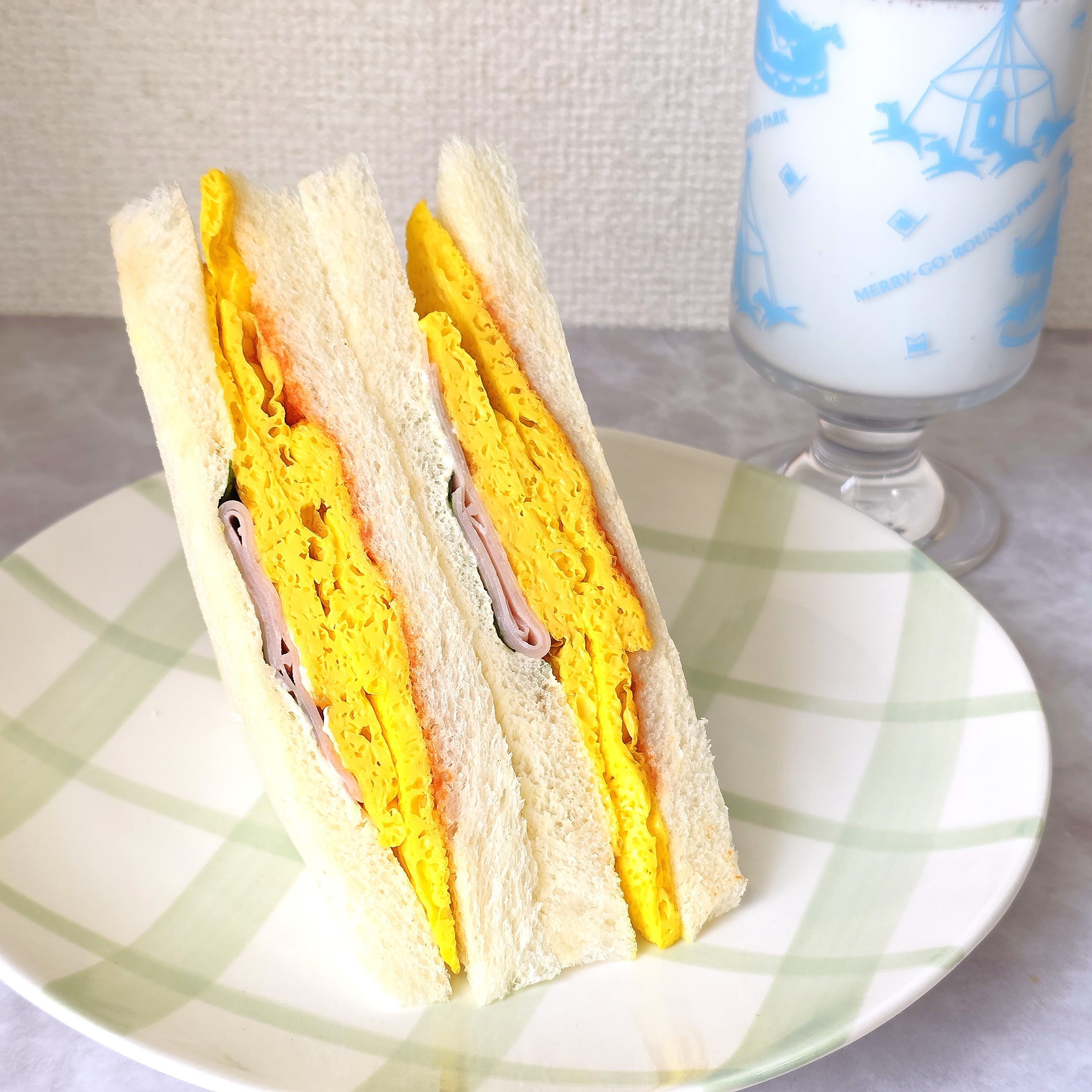 皿に乗ったボリュームたっぷりの卵サンドと隣に置かれたグラスミルク。