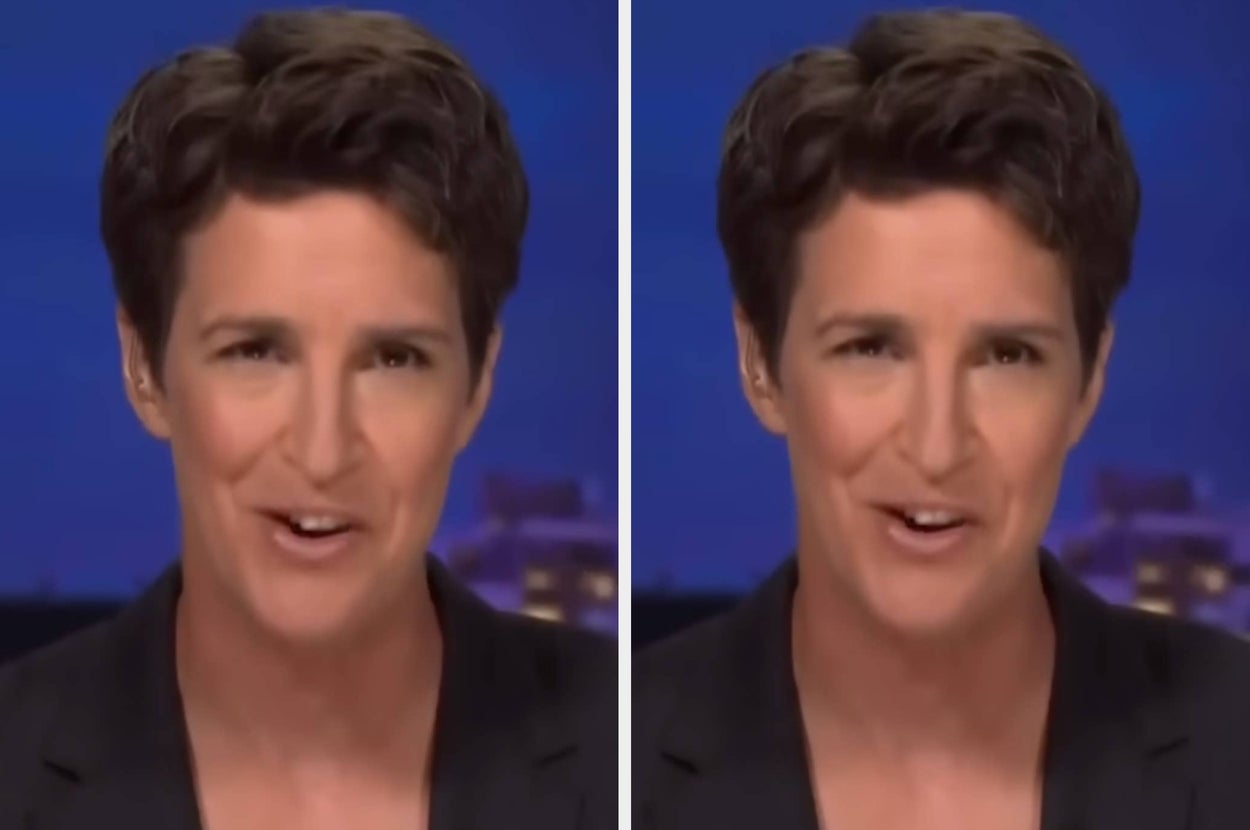 A person with short hair speaks on a TV show, wearing a dark blazer