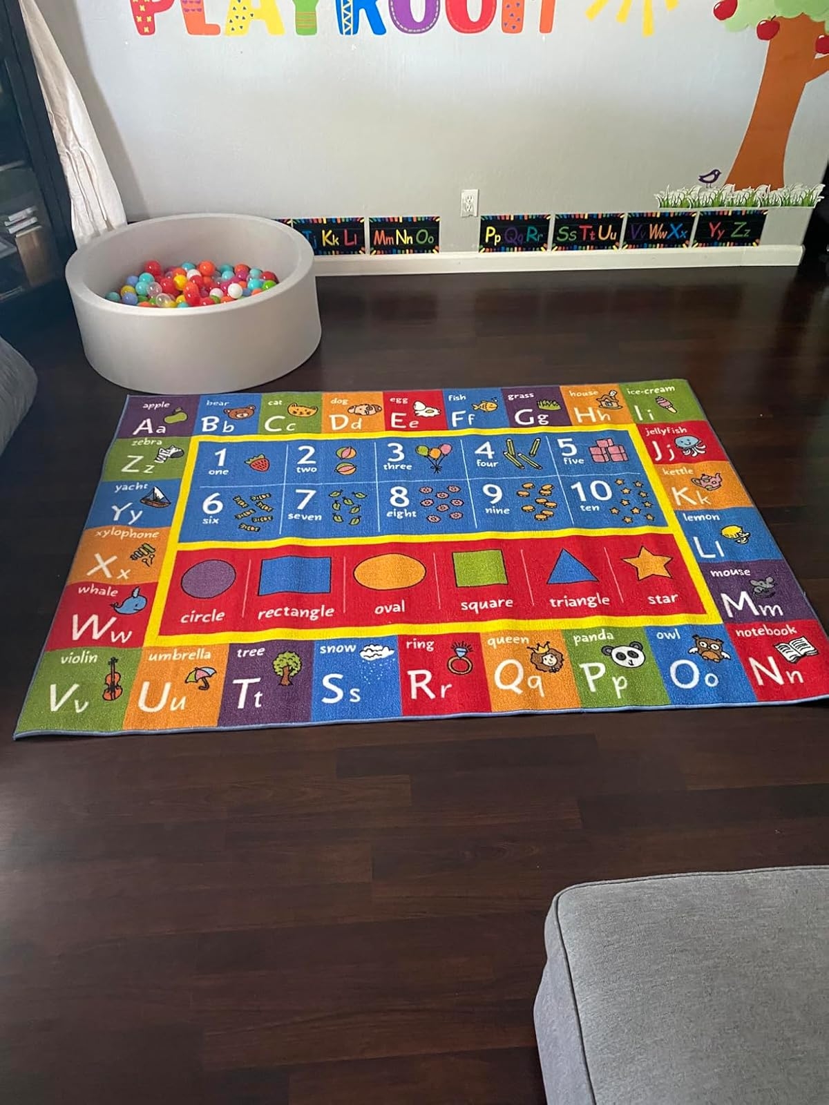 Alphabet and number rug in playroom with educational toys and wall decorations