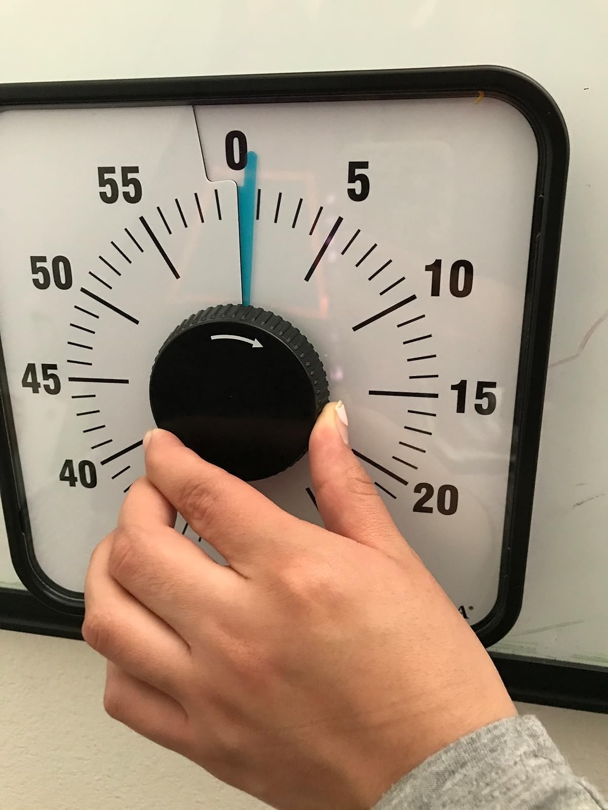 Hand adjusting a timer's dial, set near zero, in a shopping context