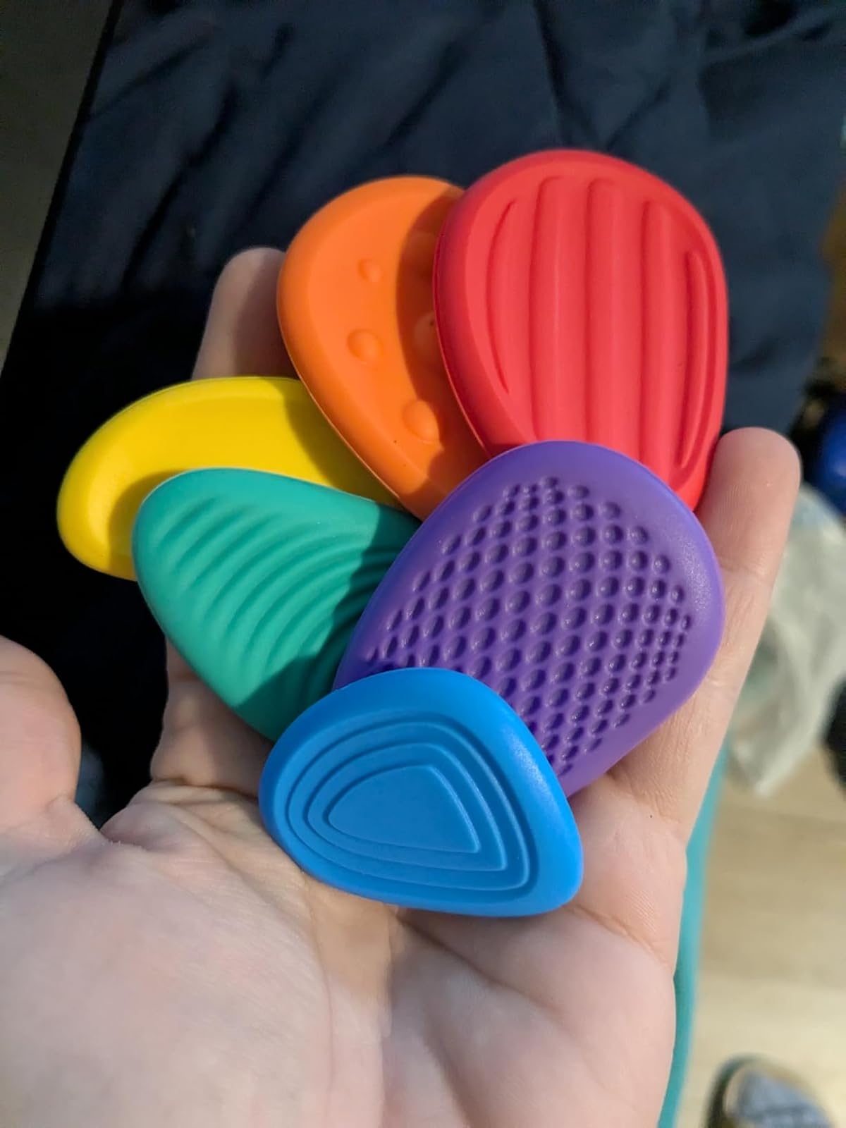 Hand holding colorful, textured rubber shoe inserts designed for comfort and support