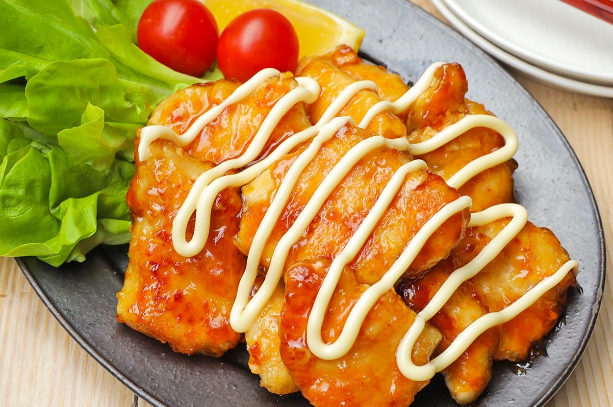 皿の上に鶏肉の照り焼きがマヨネーズで飾られ、レタスとトマトが添えられている。