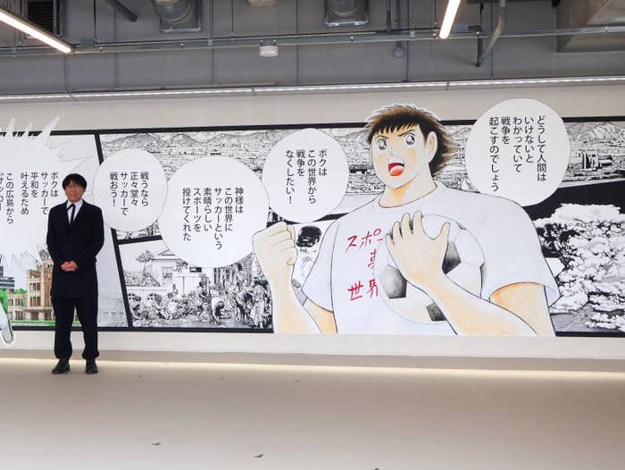 『キャプテン翼』の主人公が描かれた「エディオンピースウイング広島」の壁画と、作者の高橋陽一さん(時事)