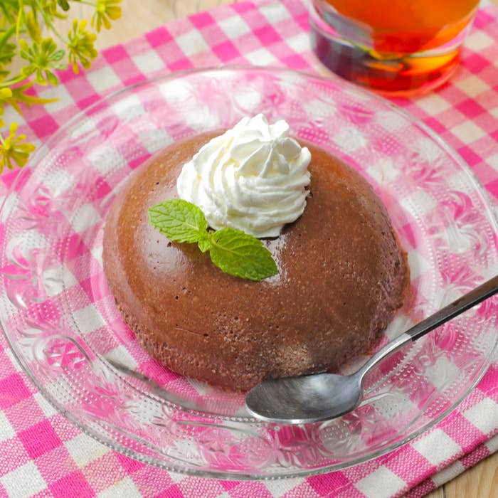 クリームとミントをトッピングしたチョコレートデザートが皿に盛られている。横にスプーンがある。