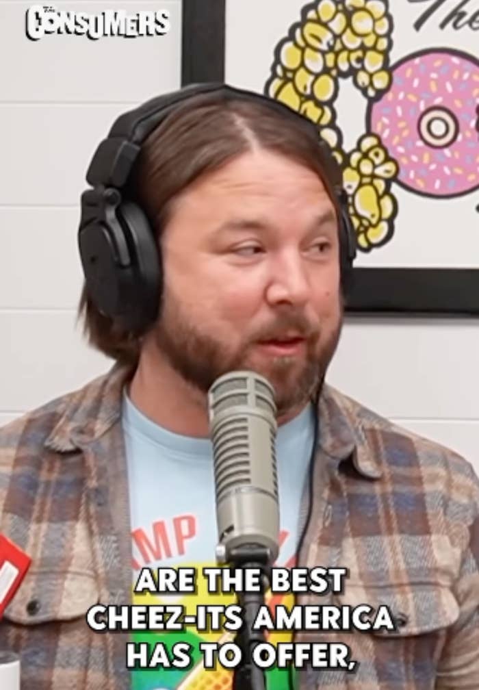 Person in a podcast studio speaking into a microphone, wearing headphones and a casual flannel shirt. Text reads, "ARE THE BEST CHEEZ-ITS AMERICA HAS TO OFFER."