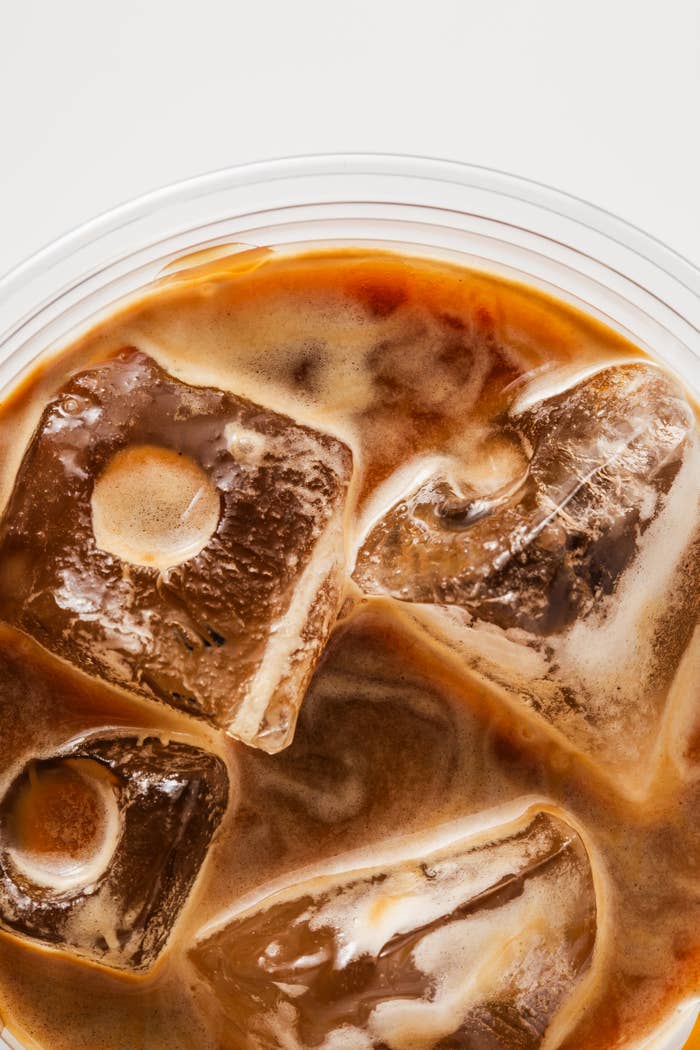 Close-up of iced coffee with large ice cubes in a clear plastic cup
