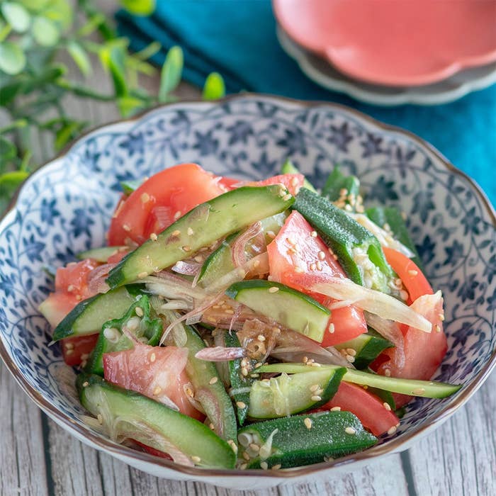 キュウリとトマトのサラダが器に盛られている。ゴマがトッピングされ、フレッシュな野菜が食欲をそそる。