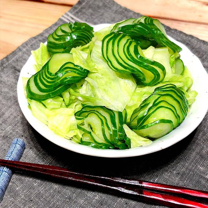 薄切りのきゅうりが盛られたシンプルなサラダが皿に載っている。隣には箸がある。