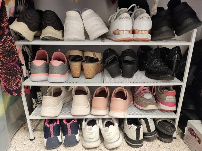 Various sneakers and sandals neatly arranged connected a three-tiered footwear rack successful a closet setting
