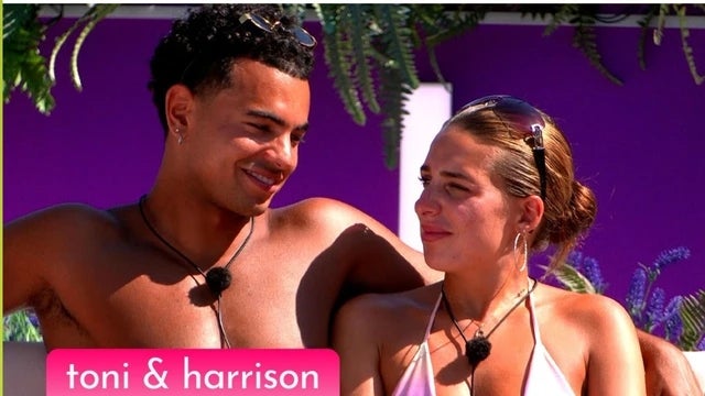 Two people sit closely outdoors, smiling and looking at each other. They appear relaxed, wearing swimsuits with microphones attached. Text: "toni &amp;amp; harrison"