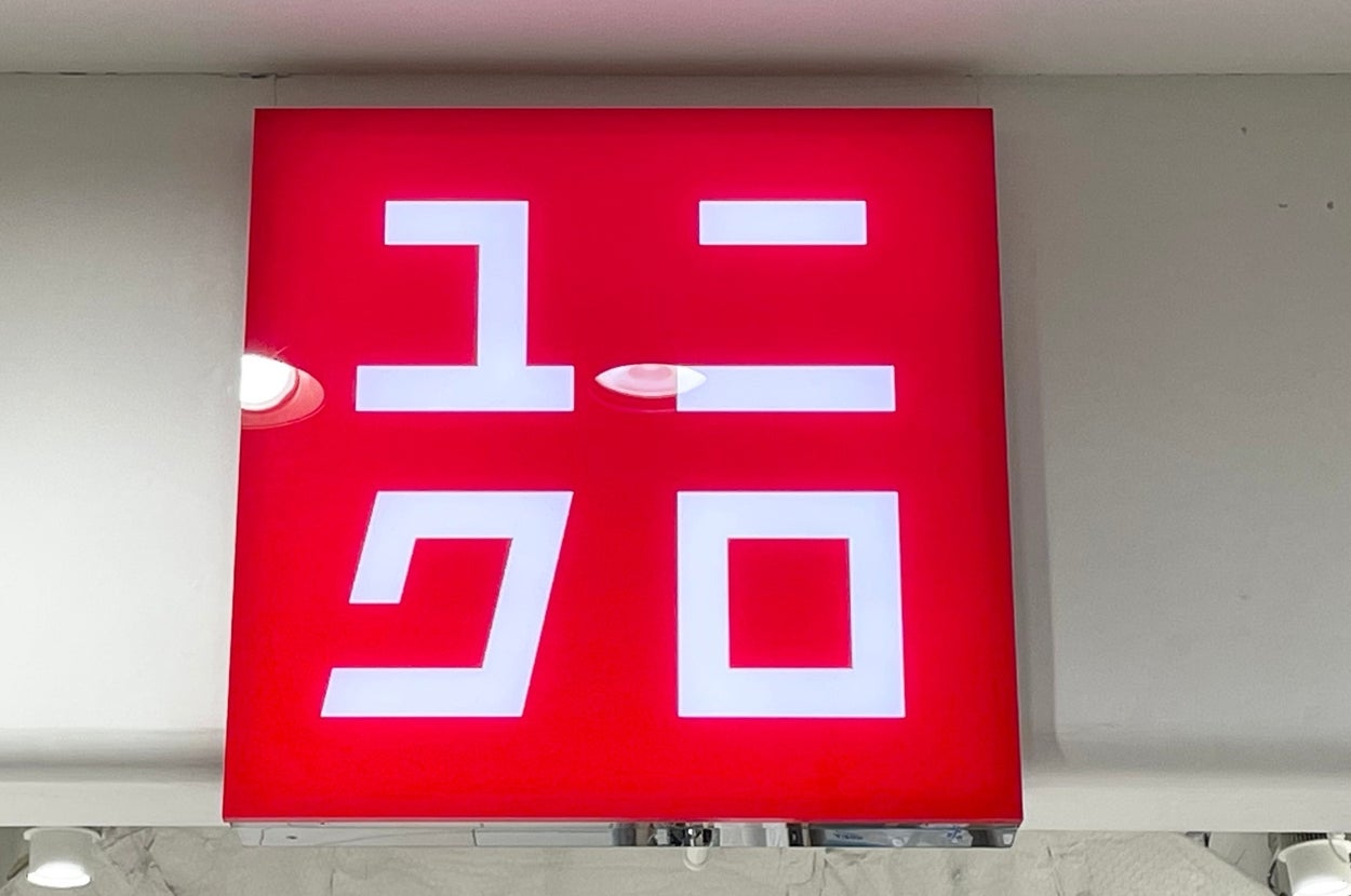 Store sign with Japanese katakana characters for "Uniqlo" in bold font on a red background, seen indoors